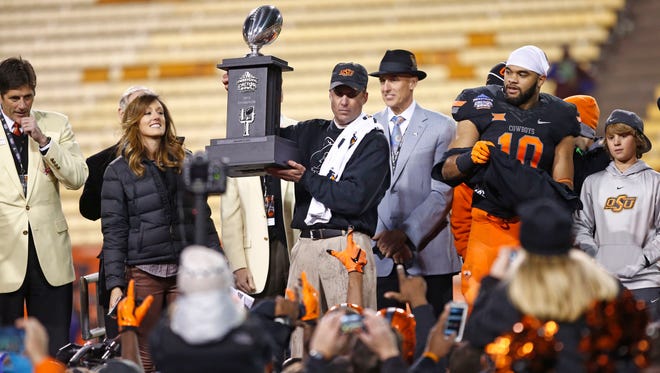 Oklahoma State head coach Mike Gundy holds-up the trophy after defeating Washington on Friday, Jan. 2, 2015 at the Ticket City Cactus Bowl in Tempe, AZ.